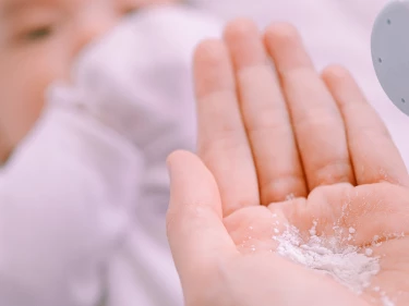 Parent applying talcum baby powder to infant, representing talc product liability personal injury cases