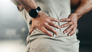 Person clutching lower back in pain highlighting need for a personal injury or workers