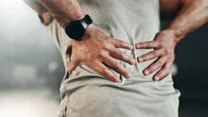 Person clutching lower back in pain highlighting need for a personal injury or workers