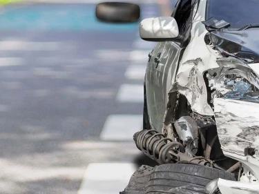 Severely damaged white car with a crushed front end after a collision, illustrating the property damage and serious injuries that can result from a car accident