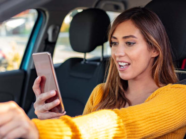 A woman texts while driving, unaware of distracted driving facts and dangers.