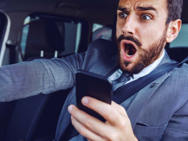 Driver using a mobile phone while driving a car, one of many examples of distracted driving.