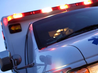 Ambulance with flashing emergency lights responding to a car accident, representing the serious injuries that prompt victims to seek legal help from a car accident attorney