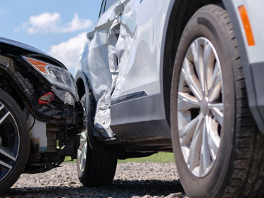 Low-angle view of two vehicles with significant collision damage, representing car accidents involving uninsured or underinsured motorists