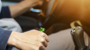 Man driving while holding a beer bottle