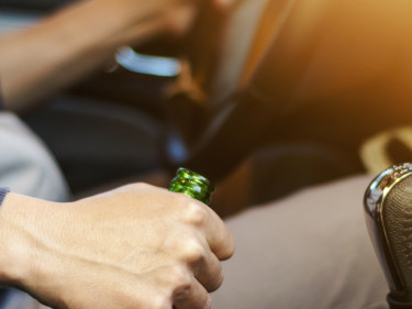 Man driving while holding a beer bottle