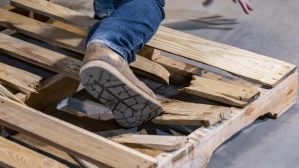 Person falling through broken wooden pallet on warehouse floor in workplace slip and fall accident