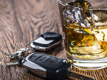 Glass of liquor with car keys