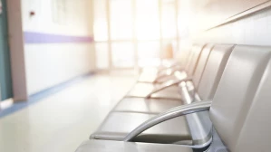 Empty hospital waiting room with rows of chairs along sunlit corridor in medical facility