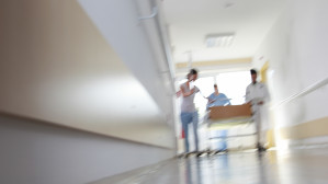 Blurred hospital corridor with medical staff and patient visible in the distance during emergency response