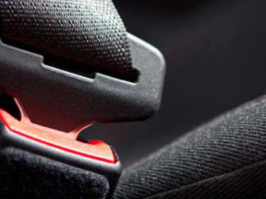 Fastened vehicle seat belt with red buckle release illustrating auto safety restraint defect litigation
