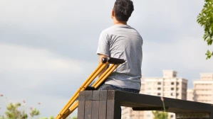Injured man sitting on park bench with crutches after a personal injury accident