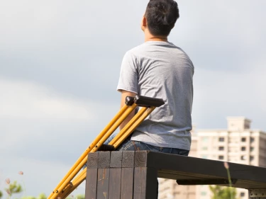 Injured man sitting on park bench with crutches after a personal injury accident