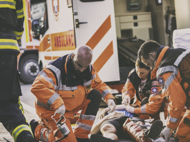 Paramedics and firefighter providing emergency care to accident victim at personal injury scene