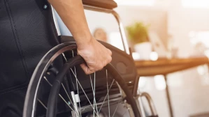 Person propelling wheelchair indoors representing mobility impairment caused by a serious personal injury