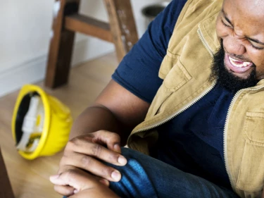 Construction worker in pain on floor clutching knee after a workplace personal injury accident