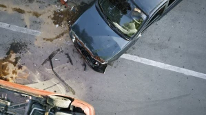 Aerial view of a car accident with one vehicle overturned and fluid spilled on the road, depicting the catastrophic results of high-impact collisions that lead to injury claims