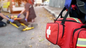 First responder rushing medical bag to accident scene where paramedics treat personal injury victim