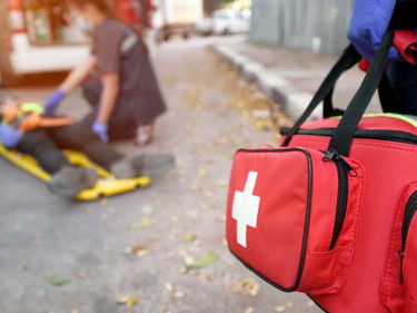 Paramedics on the scene of a personal injury administer emergency aid to a victim on a stretcher.