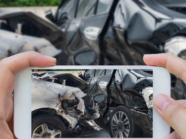 A person uses a smartphone to take a photo of vehicle damage after a crash, gathering evidence to support a personal injury claim.