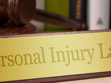 Gold desk plaque reading Personal Injury Law beside a gavel in a law office setting