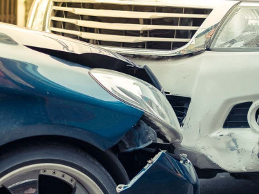 Blue car with a crumpled front end embedded into the bumper of a white truck, depicting the common front-end and rear-end collision types that give rise to car accident injury claims