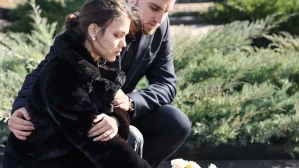 A young man and woman dressed in black place flowers on a grave, representing the outcome of common wrongful death examples.