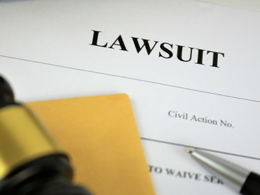 Wrongful death lawsuit paperwork sits under a gavel and pen.